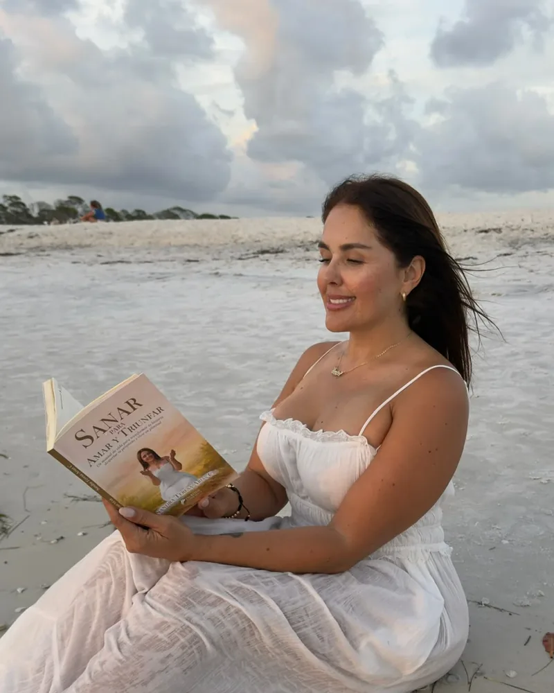 Sandra Arias leyendo Sanar para Amar y Triunfar frente al mar